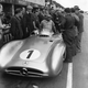A black and white photo of Fangio climbing out his Mercedes F1 car.